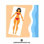 Kvinne som soler seg på stranden